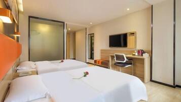 A hotel room with two beds, a desk, a chair, a television, and a large mirror.