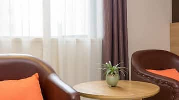 A room with two leather armchairs, a small wooden table with a potted plant, and sheer curtains.