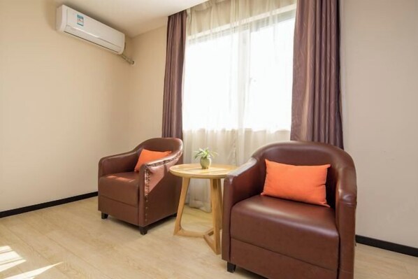 A room with two leather armchairs, a small wooden table with a plant, and an air conditioning unit on the wall. - 7 Days Premiuml (Shenzhen Longgang Universiade Center Ailian subway station) (Shenzhen)