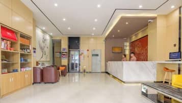 A hotel reception area with a marble counter, seating, and a reception desk.
