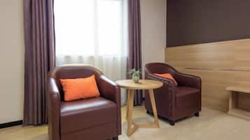 A modern room with two leather armchairs, a small wooden table, and a large window with curtains.