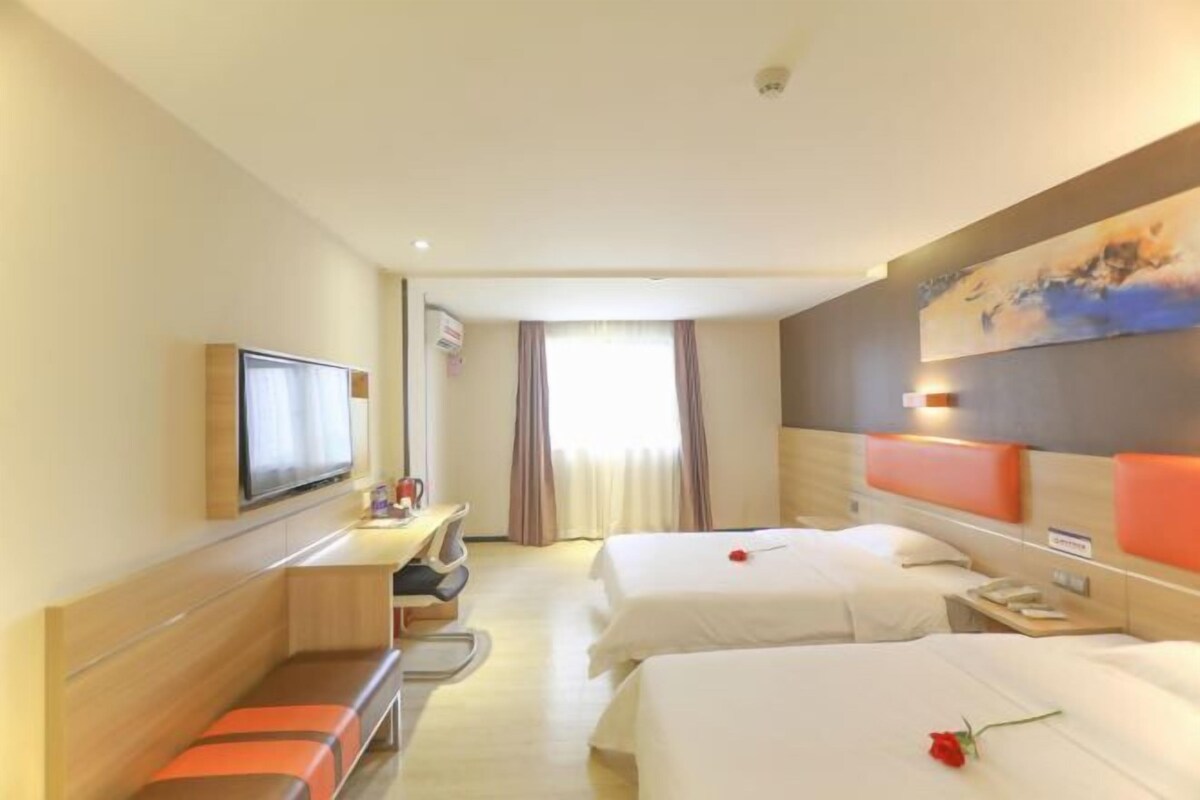 A hotel room with two beds, a desk, a TV, and a painting on the wall.