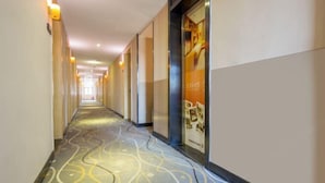 A hotel corridor with a patterned carpet, light-colored walls, and a poster on the right wall. - 7 Days Premiuml (Shenzhen Longgang Universiade Center Ailian subway station) (Shenzhen)