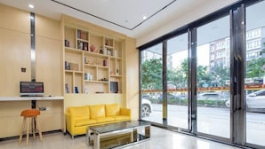 A modern lobby with a yellow sofa, a glass coffee table, and a bookshelf. - 7 Days Premiuml (Shenzhen Longgang Universiade Center Ailian subway station) (Shenzhen)