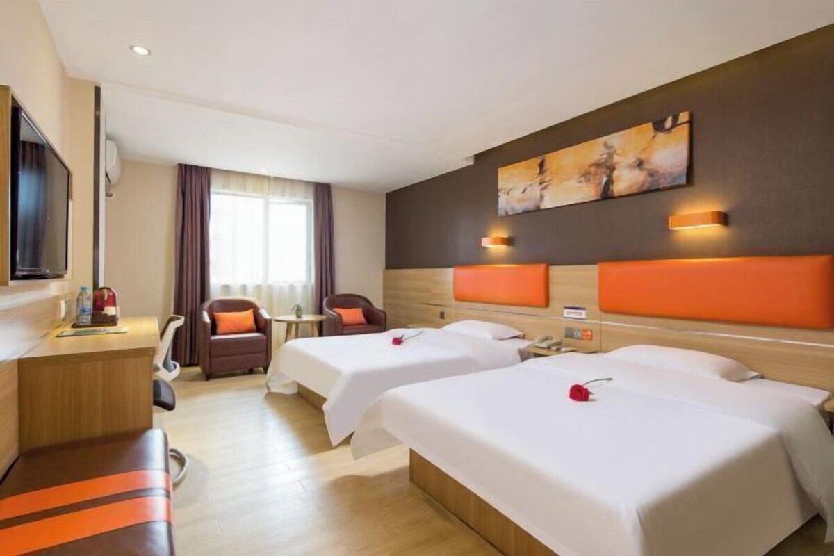 A hotel room with two beds, a desk, a TV, and a painting on the wall.