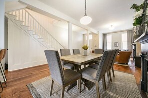 A dining area with a wooden table and six upholstered chairs, a staircase, and a living room with a sofa and a fireplace. - ★Farmhouse Style★Outdoor Patios★Parking!★Beautiful (Pittsburgh)