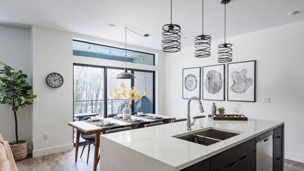 A modern kitchen with a large island, pendant lights, and artwork on the wall. - Brand new property with hot tub, fire pit, parking, covered ski storage, and more! (Silverthorne)
