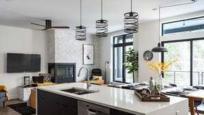A modern kitchen with a central island, a built-in dishwasher, and a dining area with a view of the outdoors. - Brand new property with hot tub, fire pit, parking, covered ski storage, and more! (Silverthorne)