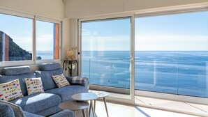 Un balcone con vista mare, un divano con cuscini decorati e un piccolo tavolo.
