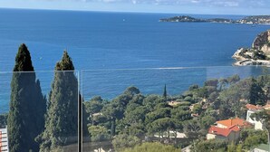 Un balcone con vista sul mare, alberi e edifici.