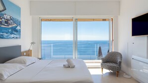 Una camera da letto con un letto, una sedia, una televisione e vista mare.