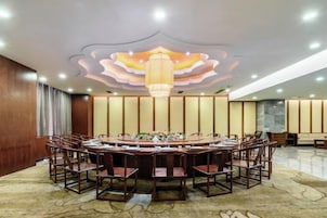 Un salón de conferencias con una mesa redonda, sillas y un techo decorativo.