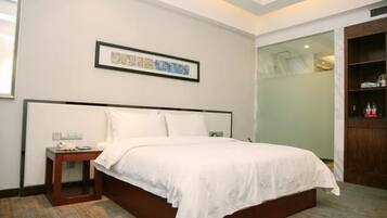 A hotel room with a bed, bedside table, and a framed picture on the wall.