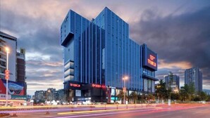 A modern building with a unique angular design, featuring vertical lines and a prominent entrance with illuminated signage. - Shehong Kuangyi Hotel (Yongyi Square) (Shehong)