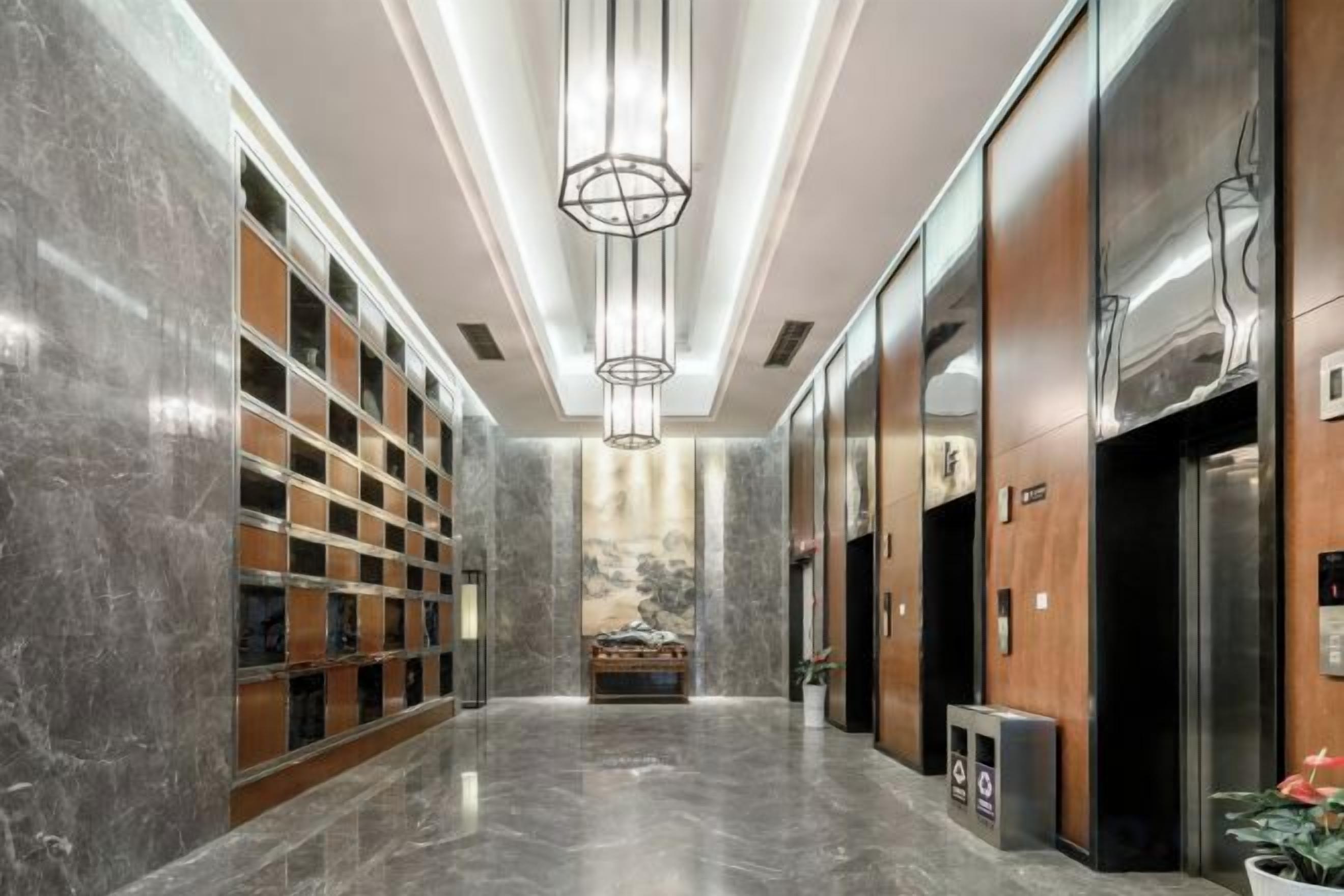 Un moderno vestíbulo de hotel con pisos de mármol, una lámpara de araña central y una recepción.
