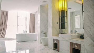 A modern bathroom with a large mirror, a bathtub, and a toilet.