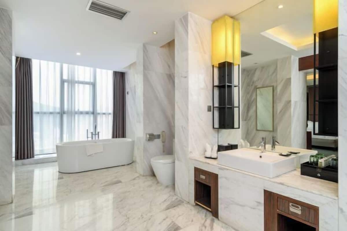 A modern bathroom with a large bathtub, a toilet, a vanity with a mirror, and a large window providing natural light.
