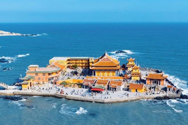 Complejo de edificios frente al mar con varias construcciones, un muelle y una zona de playa.