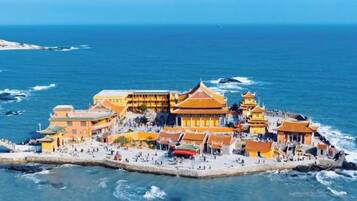 Complejo de edificios frente al mar con varias construcciones, un muelle y una zona de playa.