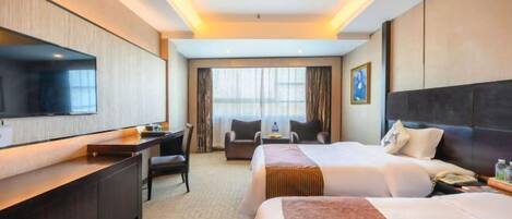 A hotel room with a large bed, a desk, a chair, a television, and a window with curtains.