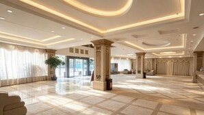 A spacious lobby with a marble floor, large columns, and a modern ceiling design. - Sunny Holiday Hotel (Shishi)