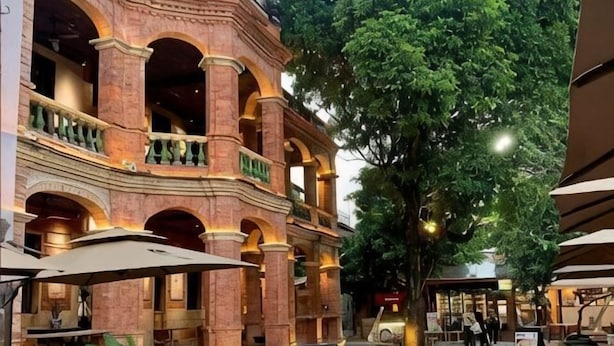 A courtyard with a brick building, outdoor seating, and trees. - Sunny Holiday Hotel (Shishi)
