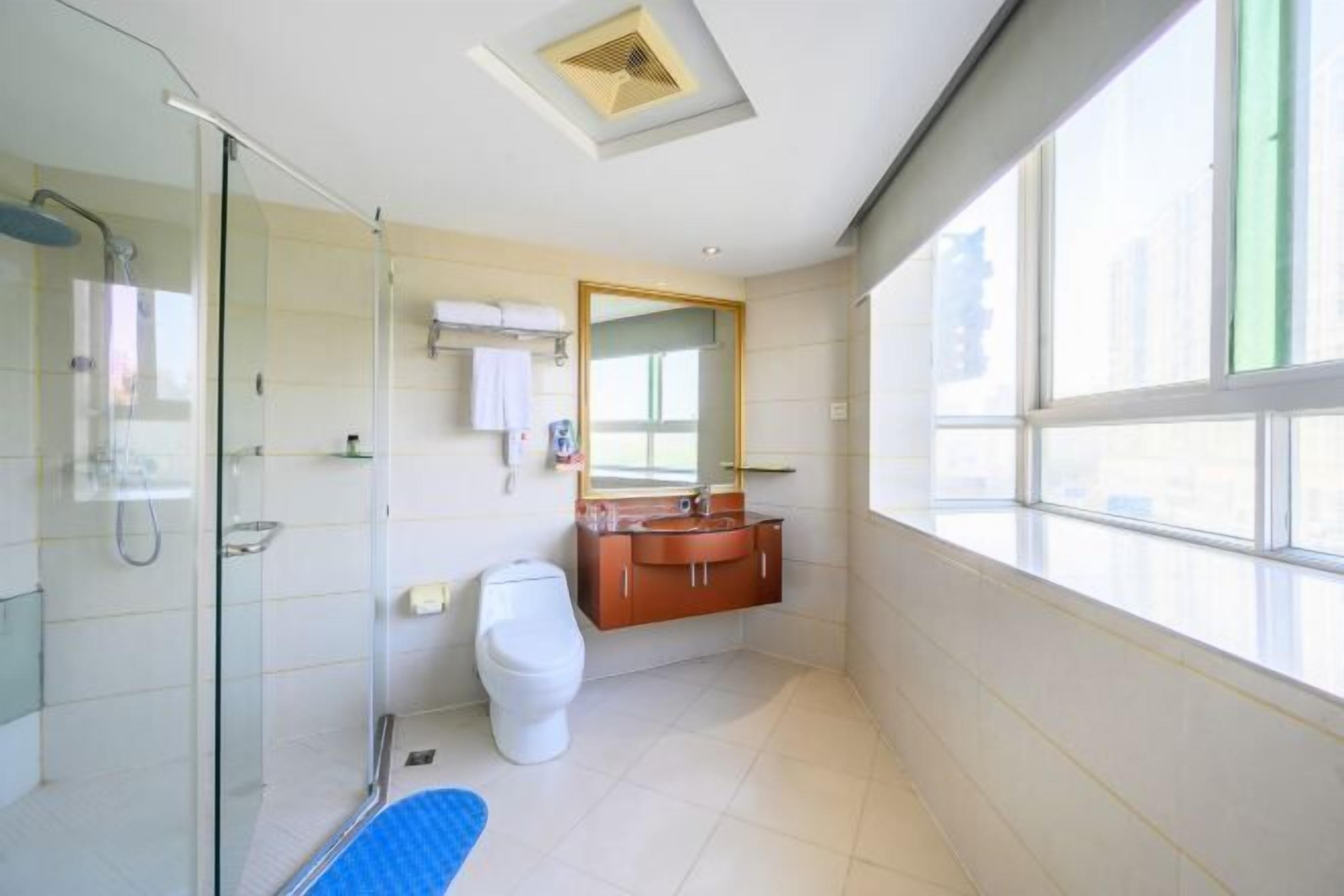 A modern bathroom with a glass shower enclosure, a white toilet, and a wooden vanity with a mirror.