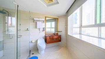 A modern bathroom with a glass shower enclosure, a white toilet, and a wooden vanity with a mirror.