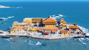 A coastal building complex with multiple structures, a fortified wall, and a beach area. - Sunny Holiday Hotel (Shishi)