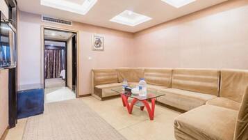 Ein modernes Wohnzimmer mit einem beigefarbenen Sofa, einem Glastisch und einer Decke mit Oberlichtern.