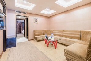 A modern living room with a beige sofa, a glass coffee table, and a ceiling with skylights. - Sunny Holiday Hotel (Shishi)