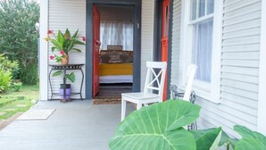 A porch with a bed, a chair, and potted plants. - Downtown Studio Gem (Nacogdoches)