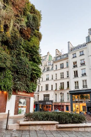 A building with a vertical garden facade, a shop named "Le Magasin Asphalte," and adjacent storefronts including "Donuts & Coffee" and "Living Packets." - 4. APARTEMENT PARIS CENTRE 50m2 2 beds - 2/4 pers. Air conditioning (Paris)