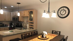 A modern kitchen with a central island, wooden cabinets, and a dining area with a wooden table and chairs. - Peaceful and Secluded! Lake Harmony Beautiful Townhome Ski Slope and Lake Views (Lake Harmony)