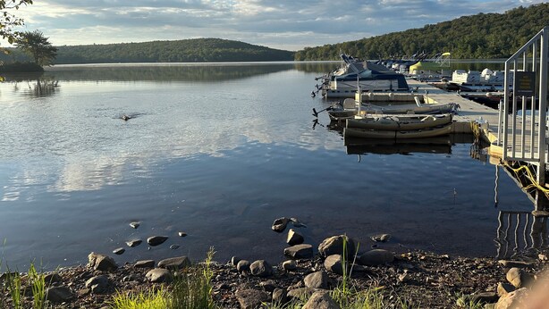 A calm lake with boats docked at a pier, surrounded by a forested hillside. - Peaceful and Secluded! Lake Harmony Beautiful Townhome Ski Slope and Lake Views (Lake Harmony)