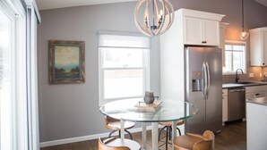 A modern kitchen with a stainless steel refrigerator, a glass dining table with chairs, and a pendant light. - Centrally Located 2BR 2BA Home - Garage Parking & Fully Equipped Kitchen/Laundry (Janesville)