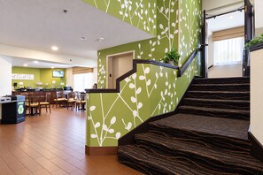 Un hall d’hôtel avec un escalier, un comptoir d’accueil et un espace repas.