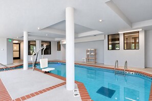 Piscina interior com superfície de água cristalina, escada e borda em azulejo.