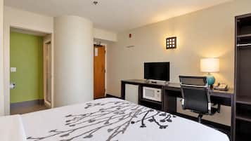 A hotel room with a bed, a desk with a computer, a microwave, and a TV.