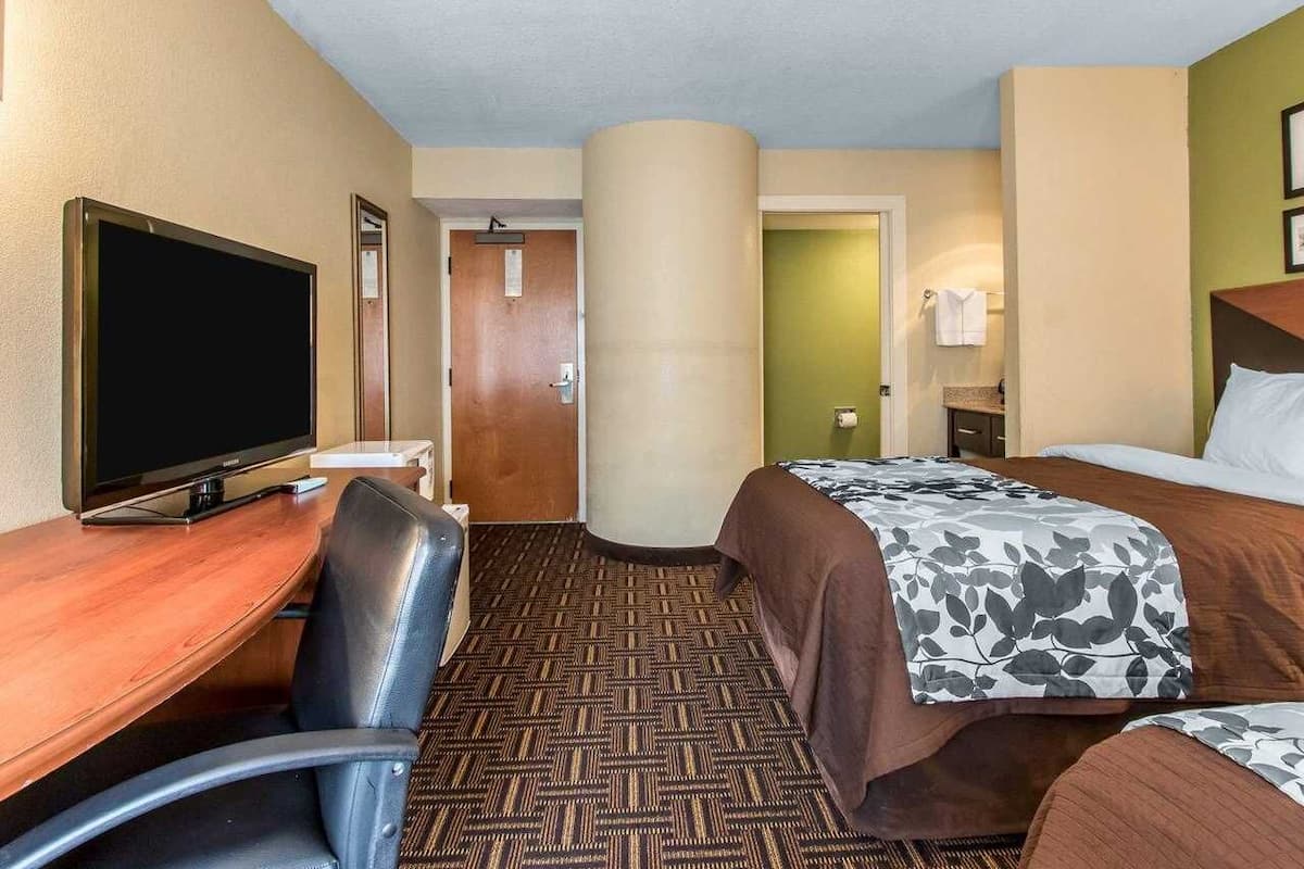 Een hotelkamer met een bed, een bureau met een televisie, een stoel en een vloerbedekking.