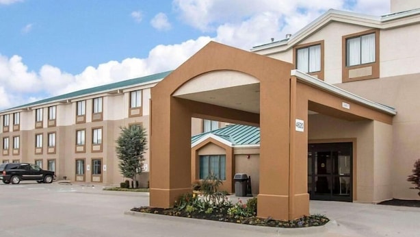 L’entrée d’un hôtel, avec un passage couvert, un espace de stationnement et une façade ornée de nombreuses fenêtres.