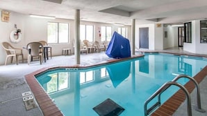 Une piscine intérieure dotée d’une zone abritée, de chaises confortables placées au bord du bassin et d’un panneau de signalisation indiquant clairement la sortie.