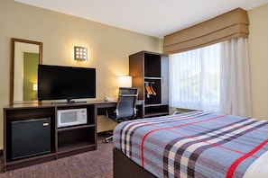 A hotel room with a bed, a desk with a television, a microwave, and a wardrobe. - The Douillet by Demeure Hotels (Oklahoma City)