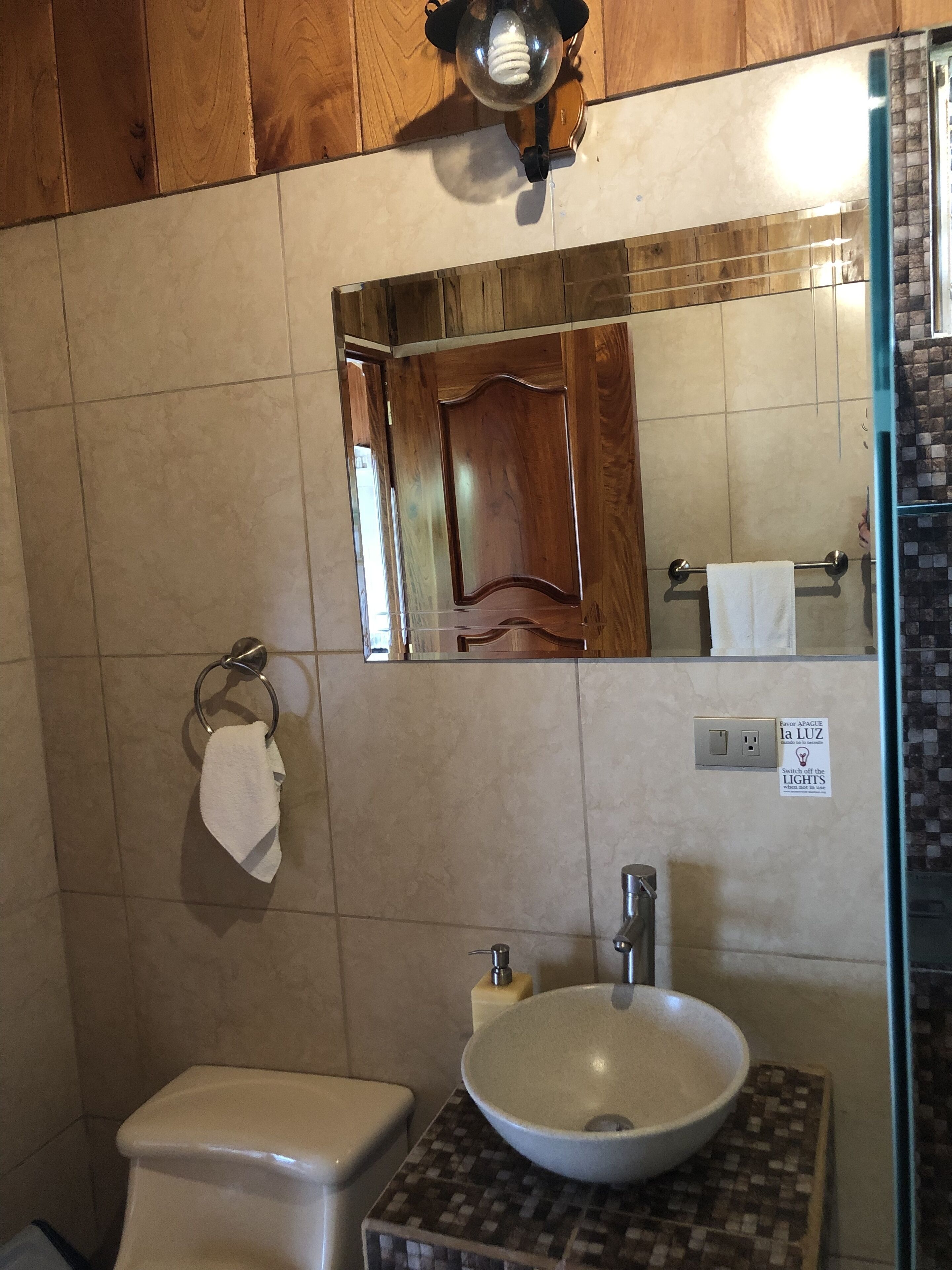 Une salle de bain équipée d’un WC, d’un lavabo, d’un miroir et d’un porte-serviettes.