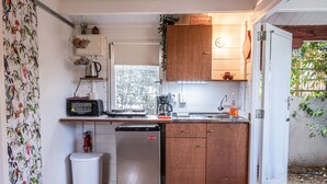 Een kleine keuken met houten kastjes, een magnetron, een koffiezetapparaat en een vaatwasser.
