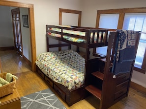 A bunk bed with a quilted mattress, wooden headboard, and a small bedside table.