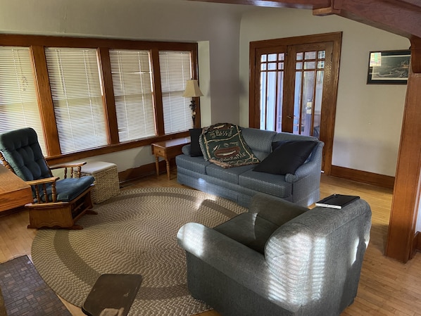 A cozy living room with a blue sofa, a wooden armchair, and a small table.