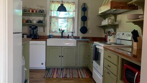 A kitchen with a sink, stove, and microwave. - The Edinburgh Cottage (Baton Rouge)