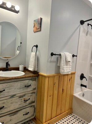 Een bad/douchecombinatie, een haardroger, handdoeken, zeep