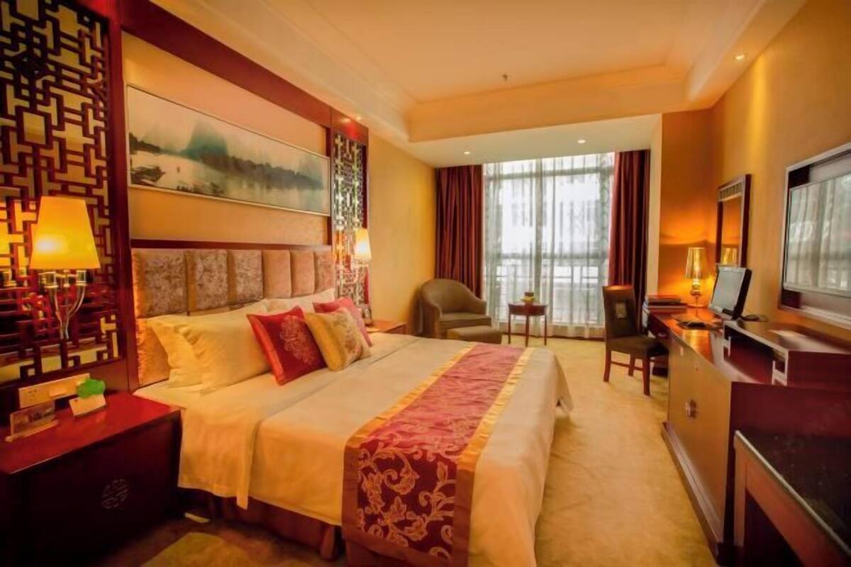 Une chambre d’hôtel avec un grand lit, un bureau avec un ordinateur, une chaise et un téléviseur.